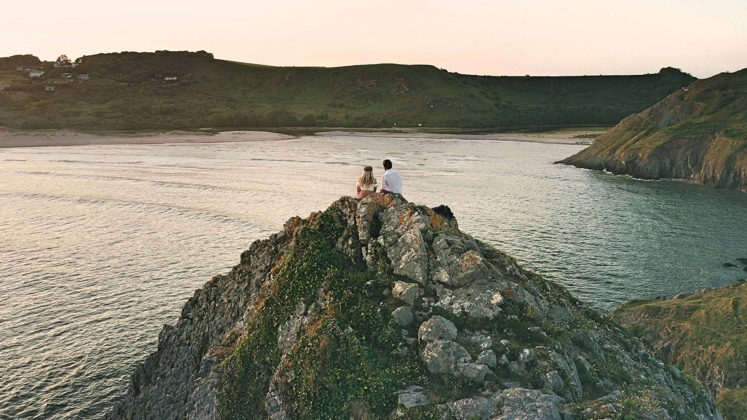 A couple sitting on a rock in the water