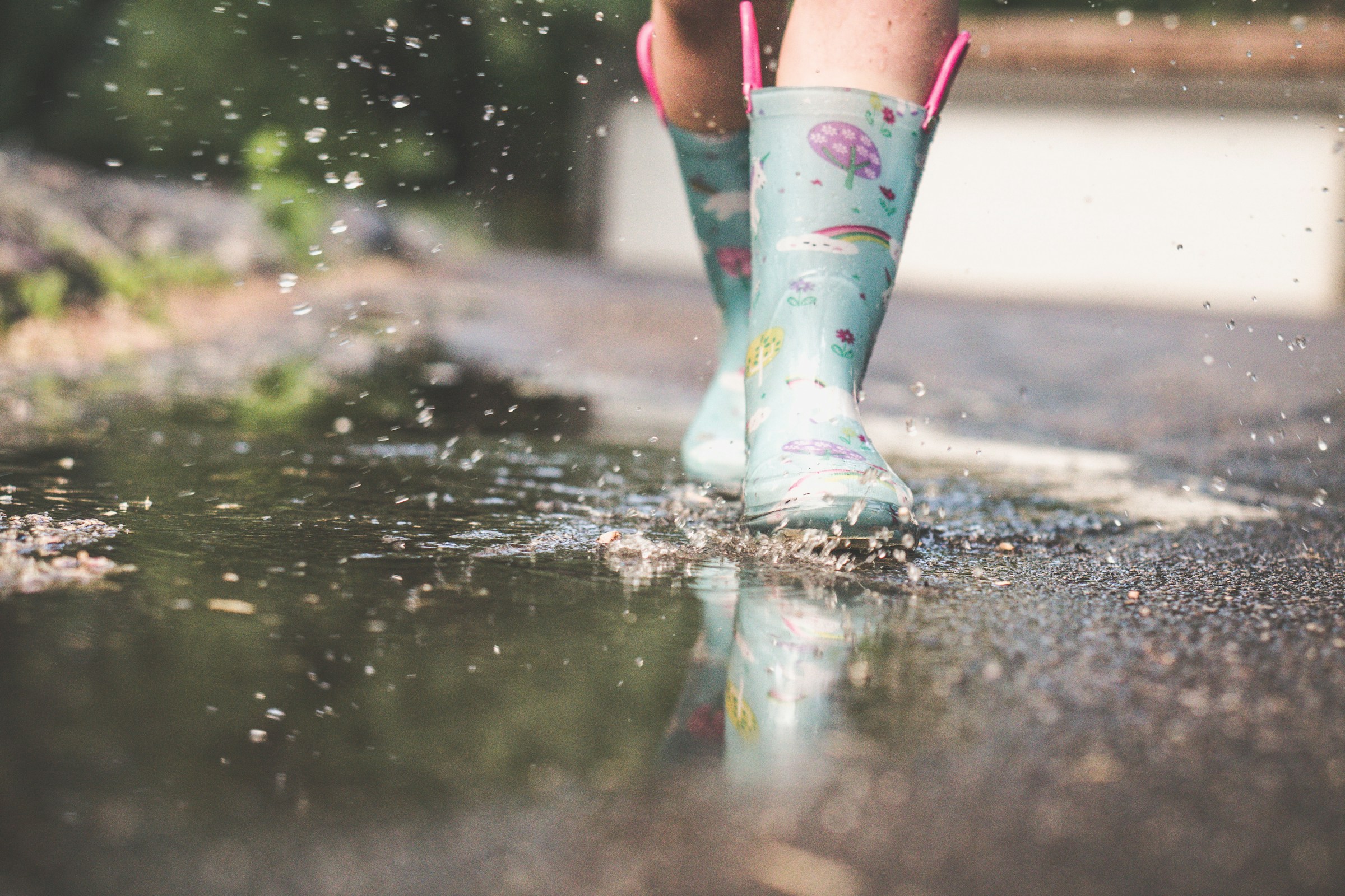 A child wearing wellie boots walking in a puddle
